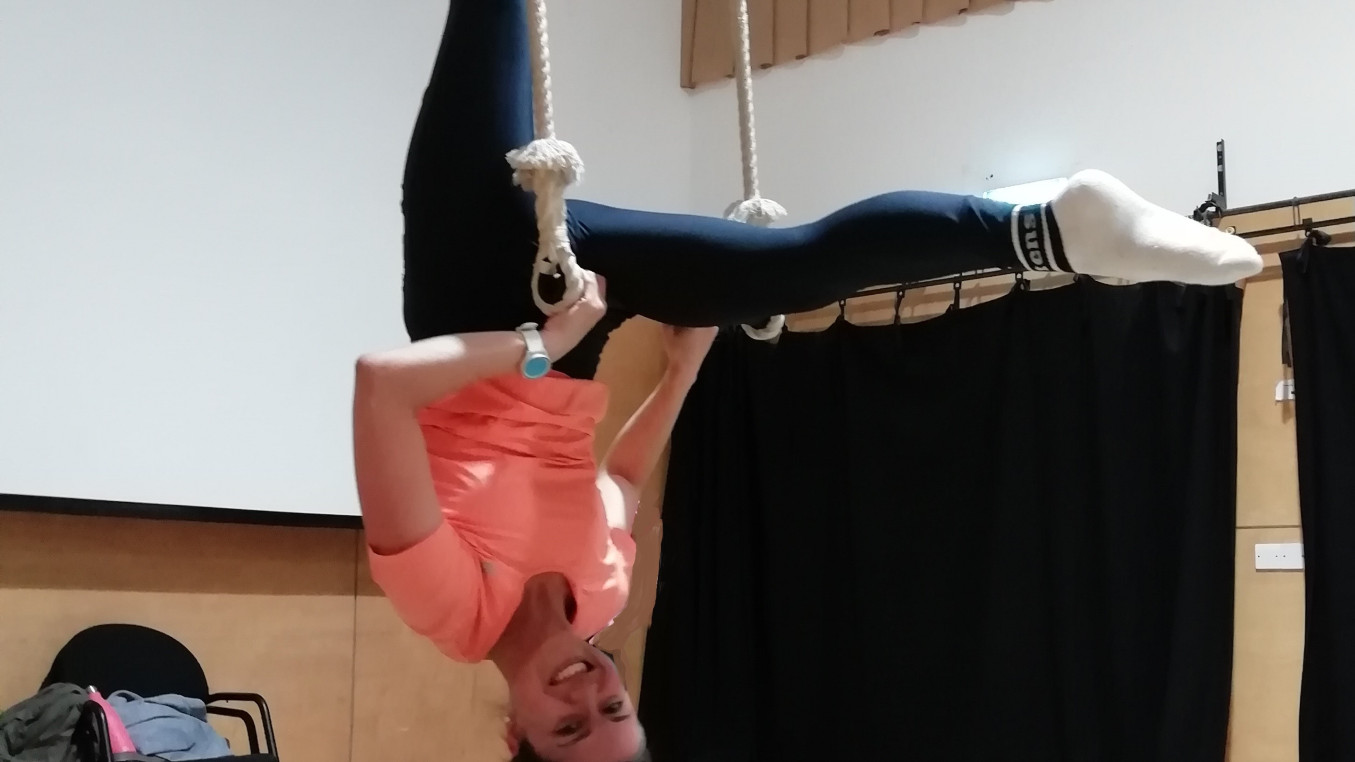 Smiling woman in L-hang pose on trapeze