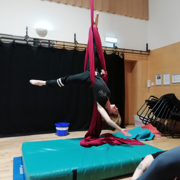 Smiling woman in modified ankle hang on silks