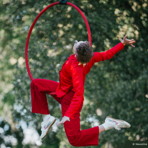 Aerial artist dressed in red hanging in red hoop
