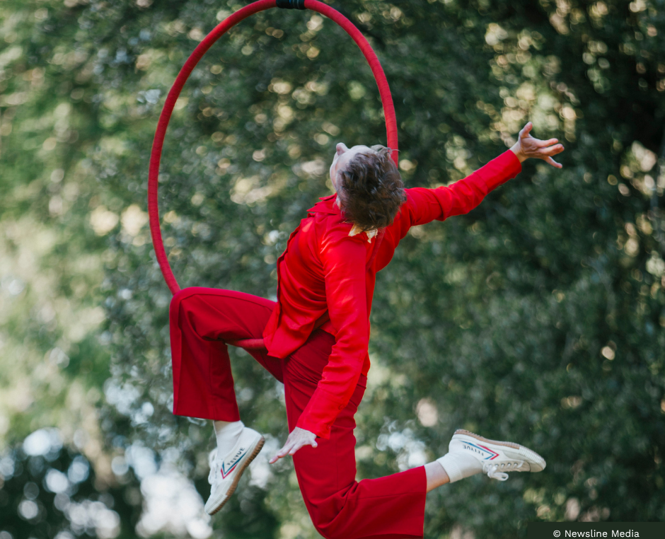 Aerial artist dressed in red hanging in red hoop