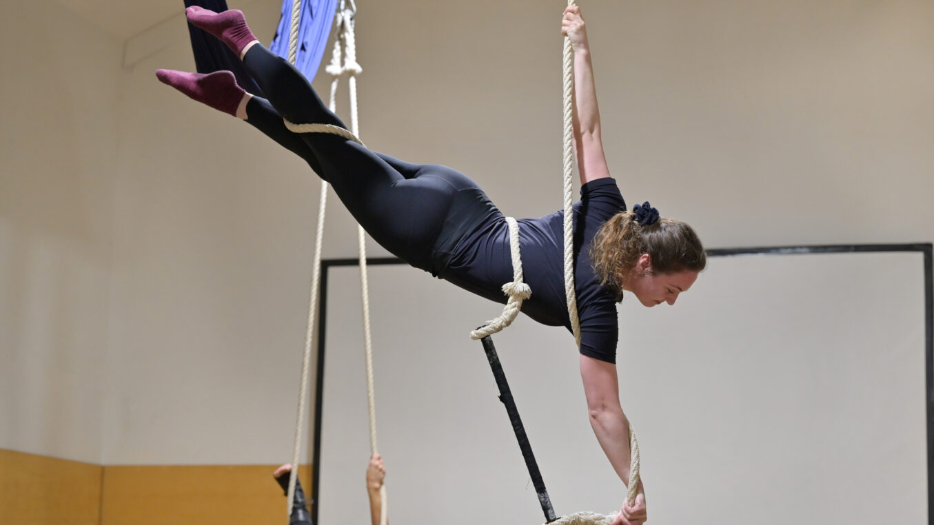 A woman in leaping salmon position on a trapeze